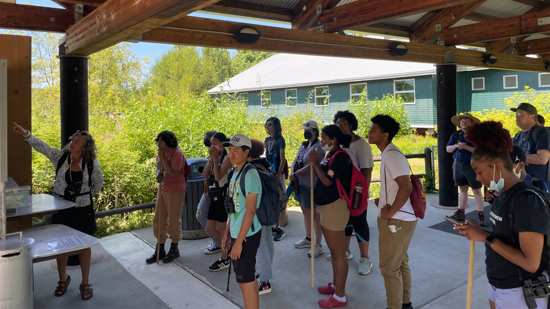 A group of youth and adults look out over a wetland